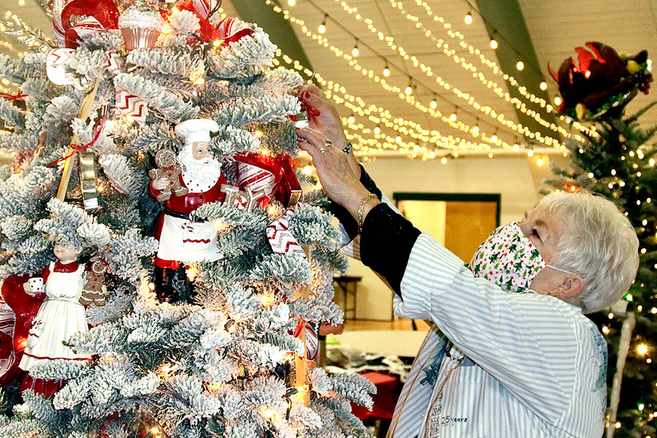 Sherry Phillips, the head of the designers group for the 31st edition of the Festival of Trees, puts another delight on her tree, called “Baking With Mrs. Santa,” earlier this week. Decorated trees will either be auctioned at the gala or by silent auction, all part of the Olympic Medical Center Foundation fundraiser inside the Vern Burton Center in Port Angeles. (Dave Logan/for Peninsula Daily News)