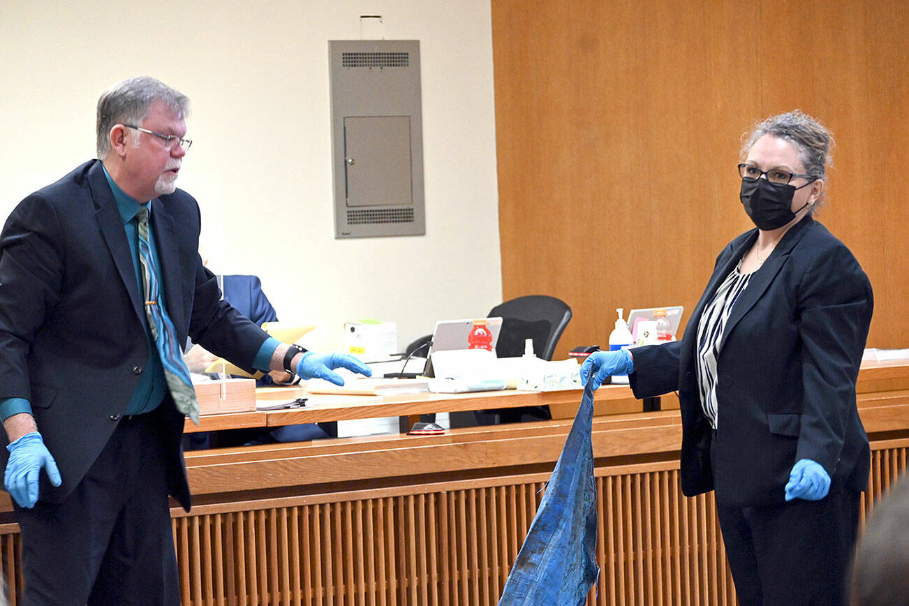 State Patrol Forensic Analyst Johan Schoeman, left, and Michele Devlin, deputy prosecuting attorney, on Monday show the jury in Dennis Bauer’s murder trial the tarp that was wrapped around the body of victim Darrell Iverson. (Paul Gottlieb/Peninsula Daily News)