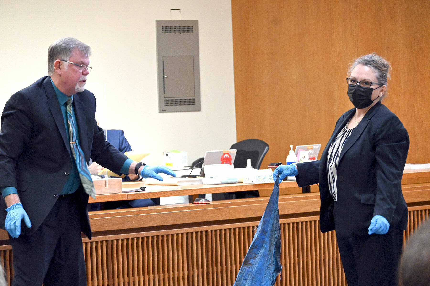 State Patrol Forensic Analyst Johan Schoeman, left, and Michele Devlin, deputy prosecuting attorney, on Monday show the jury in Dennis Bauer’s murder trial the tarp that was wrapped around the body of victim Darrell Iverson. (Paul Gottlieb/Peninsula Daily News)