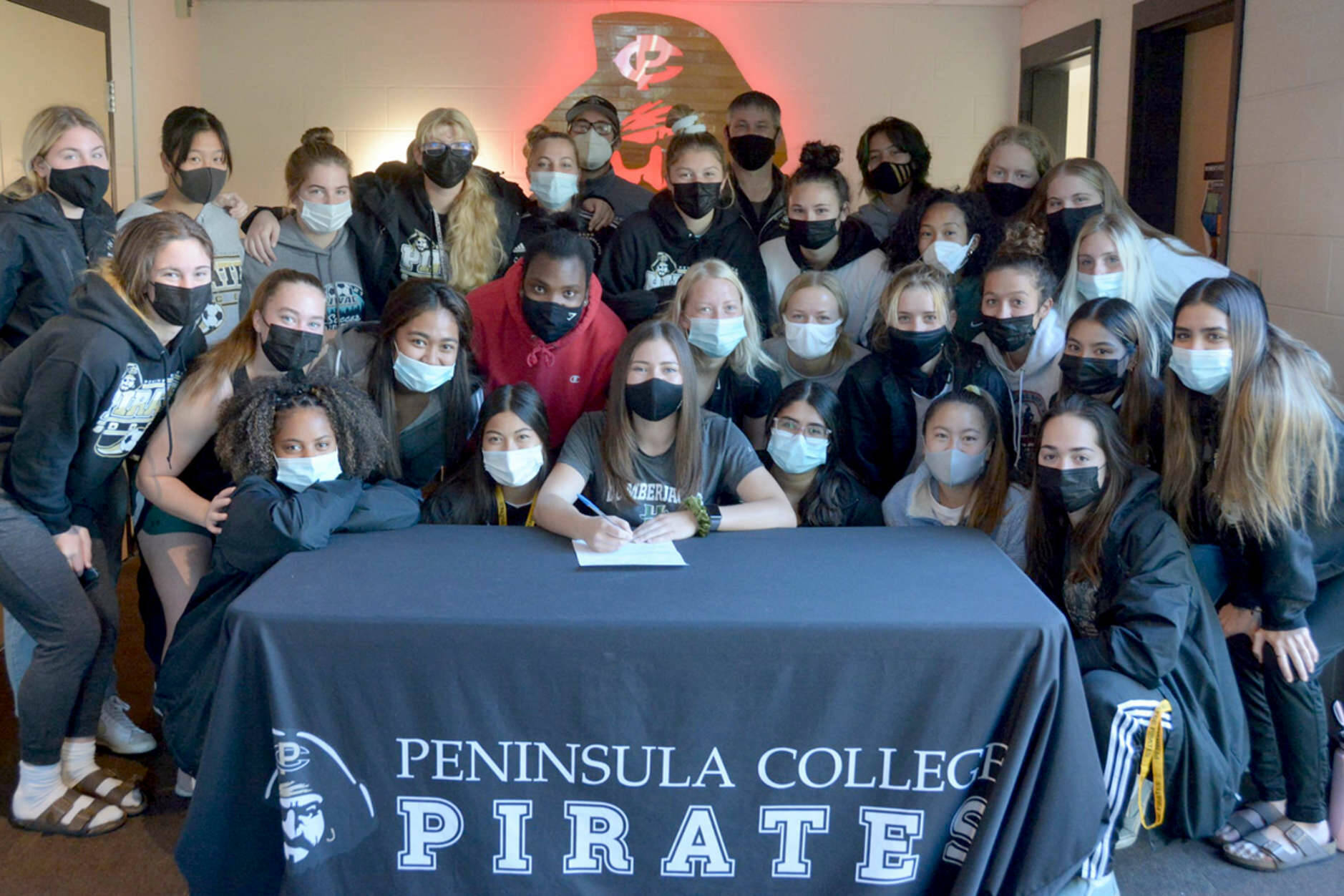 Peninsula College
Peninsula College's Grace Johnson, center, signs to play women's soccer for Humboldt State University in Arcata, Calif., late last week surrounded by her Pirates teammates after her team won the NWAC championship.