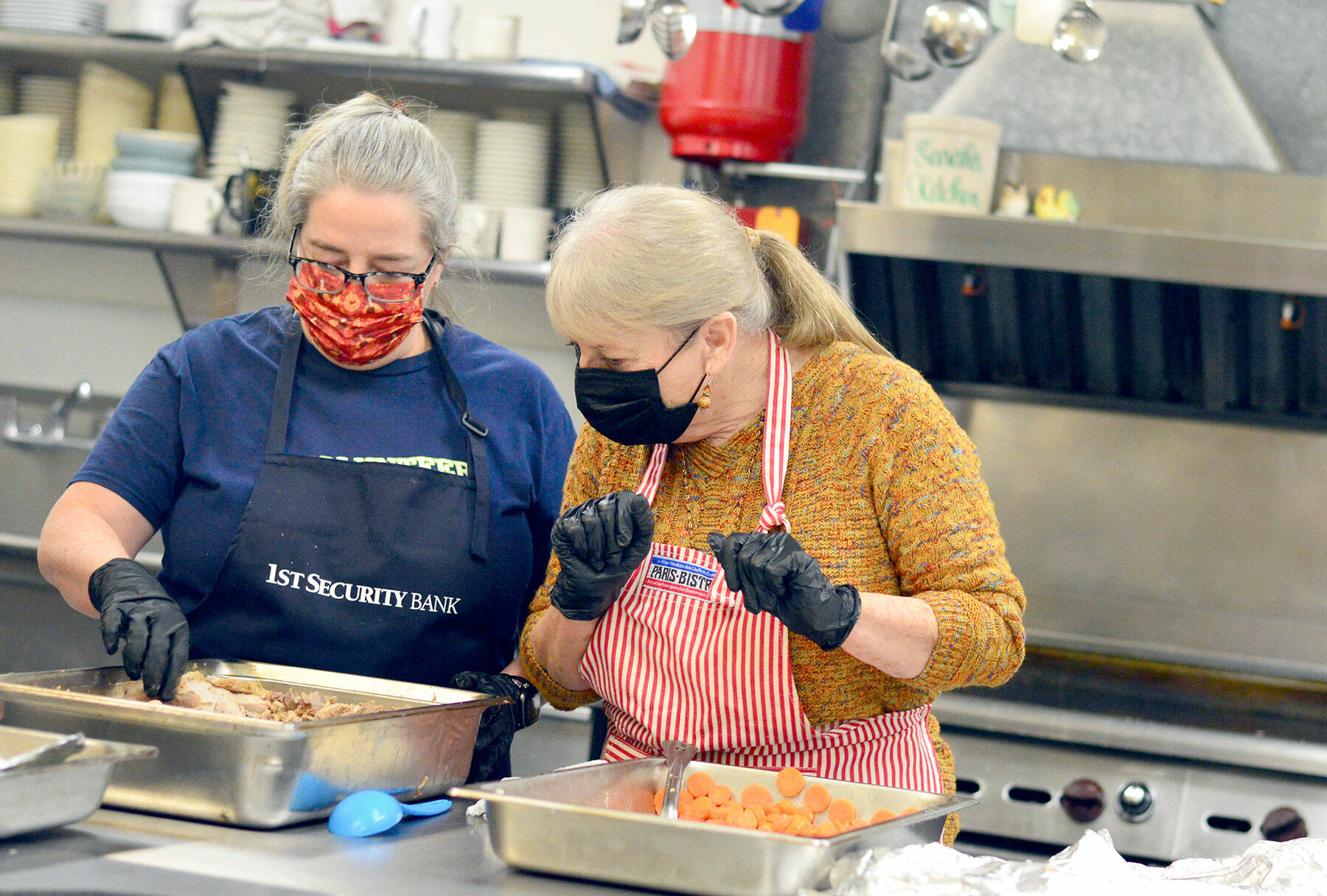Volunteers Anita Schmucker and Judy Robinett are among the veteran crew members who served hundreds of takeout Thanksgiving meals at the Tri-Area Community Center on Thursday. (Diane Urbani de la Paz/Peninsula Daily News)