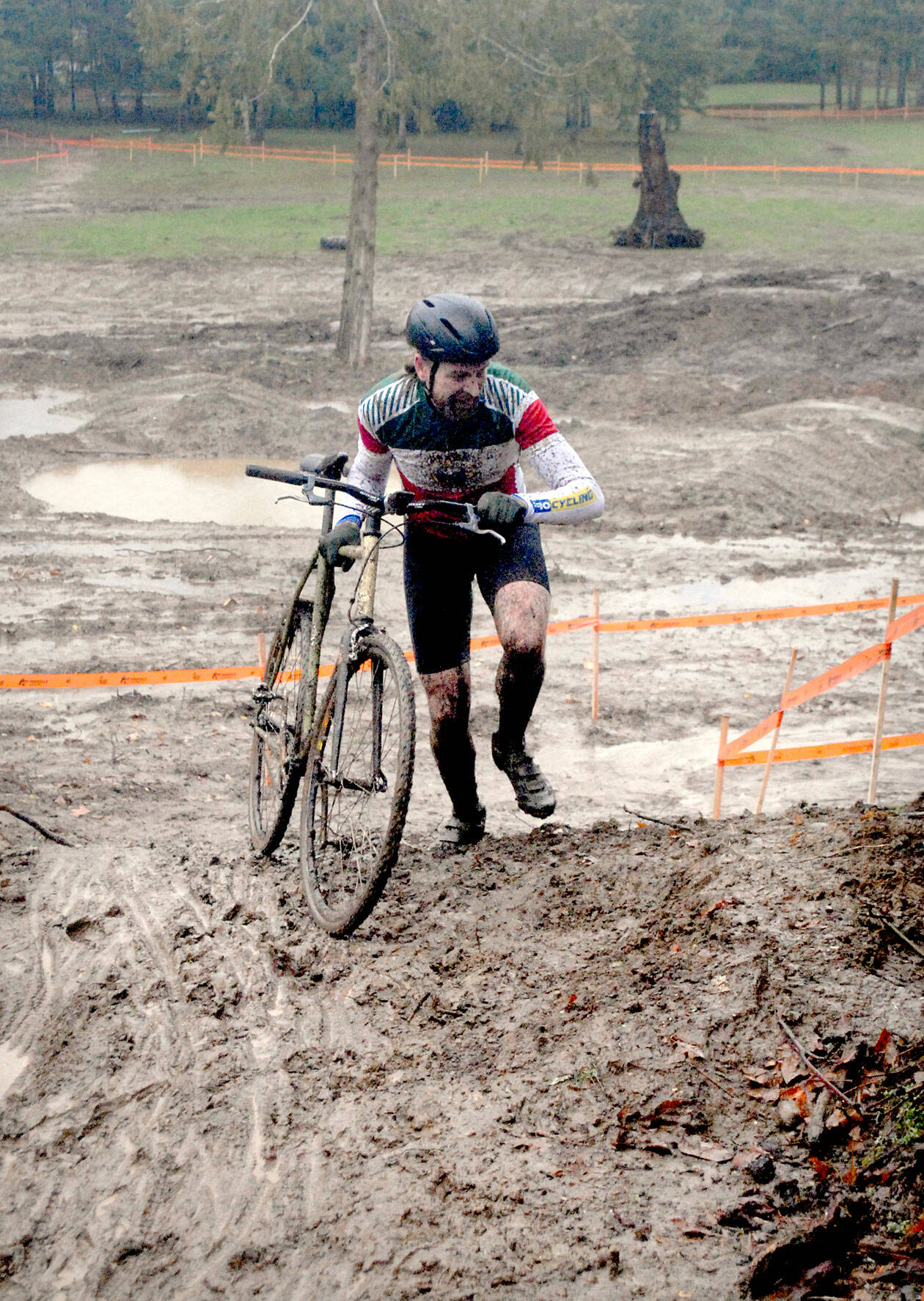 Bryan Smith of Seattle pushes his bicycle up a steep, muddy hill during Saturday’s PNW Extreme Cyclocross mens single-speed race at Extreme Sports Park in Port Angeles. (Keith Thorpe/Peninsula Daily News)