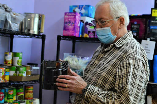 Pastor Scott Rosekrans of the Community United Methodist Church shows off one of the tiny stoves made by volunteer Jean Holtz. People without access to a kitchen can use the camp stoves to heat meals from the church’s food pantry. (Diane Urbani de la Paz/Peninsula Daily News)