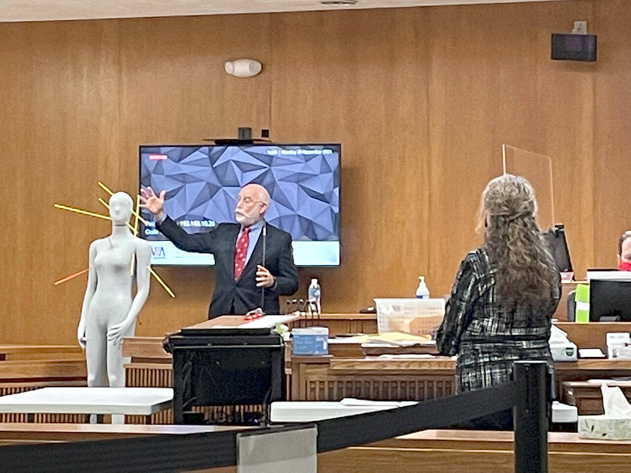 Dr. Eric Kiesel, the medical examiner who performed autopsies on the bodies of Tiffany May and Darrell and Jordan Iverson in January 2019, uses a manikin to show the trajectory of bullets during Dennis Mavin Bauer’s triple murder trial  in Clallam County Superior Court. Michele Devlin, county chief criminal deputy prosecuting attorney, looks on. (Rob Ollikainen/ for Peninsula Daily News)