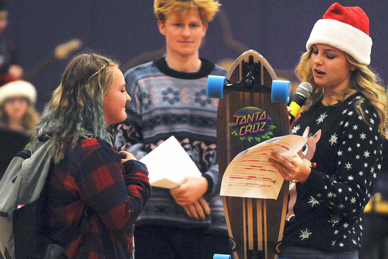 Gretta Thorson, right, presents an SHS student with a skateboard as part of the Sequim High School Winter Wishes assembly in December 2019 in this Olympic Peninsula News Group file photograph.