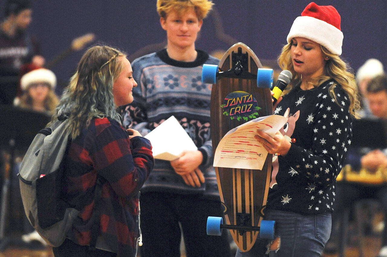 Gretta Thorson, right, presents an SHS student with a skateboard as part of the Sequim High School Winter Wishes assembly in December 2019. (Olympic Peninsula News Group file photograph)