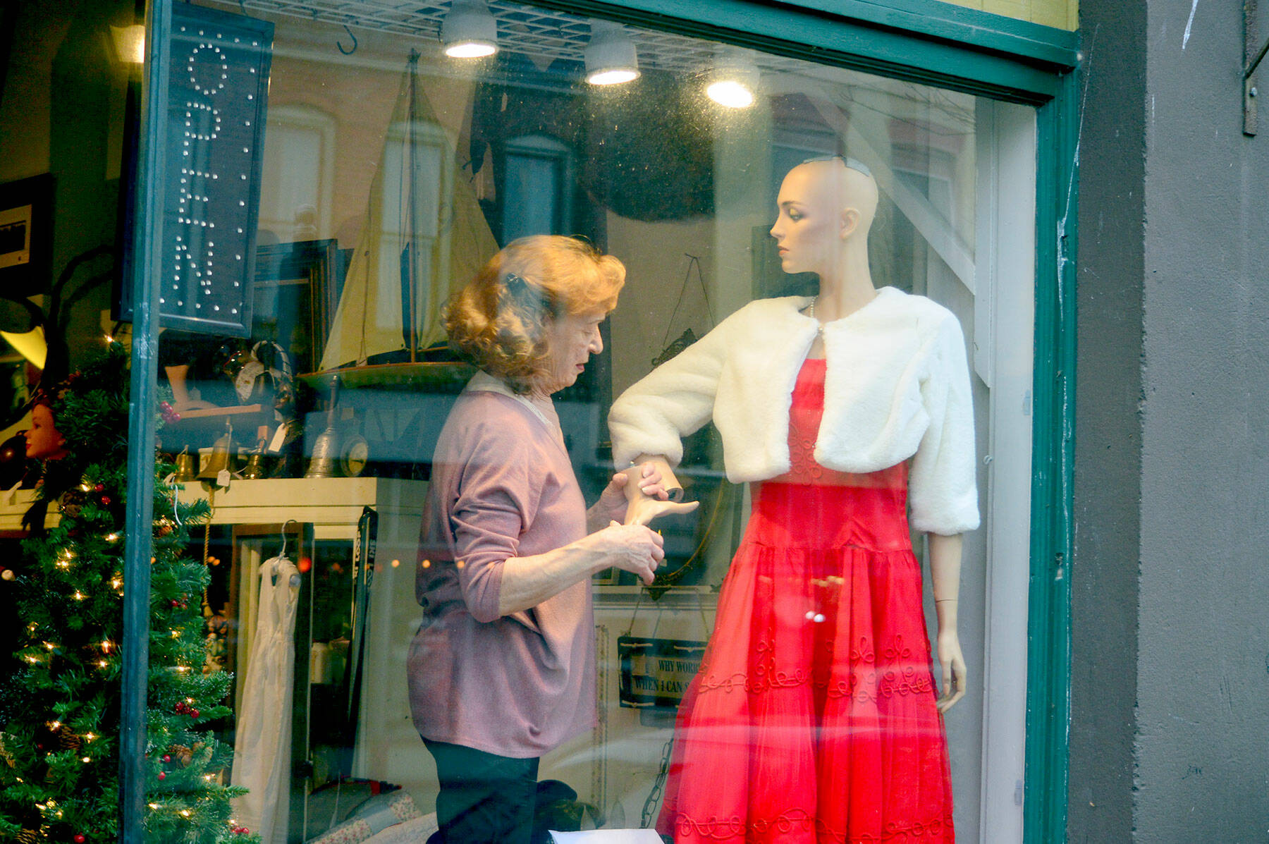 Marion Castaneda prepares a mannequin at her Deja Vu store on Water Street in Port Townsend, where the Main Street Program is organizing a variety of activities this month, including the Winter Window Wander of decorated shop windows downtown and the community Christmas tree lighting at dusk Saturday. Under and near the Tyler Street Plaza tent at Tyler and Water streets Saturday afternoon, the Wild Rose Chorale will sing, Santa will pose for photos and the Kiwanis Choo Choo train will come by. Details are found at the Port Townsend Main Street website. (Diane Urbani de la Paz/Peninsula Daily News)