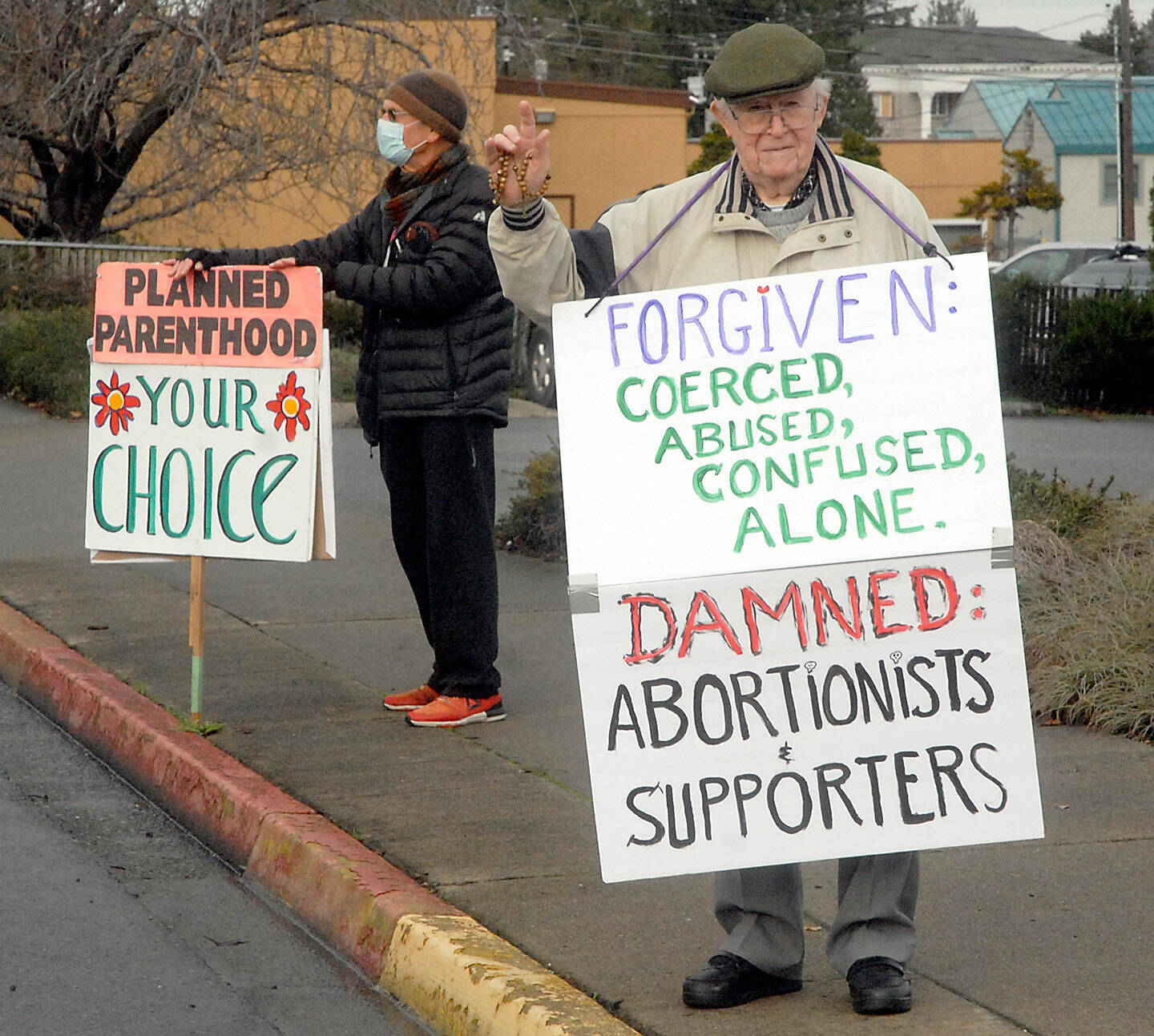 Pro-choice supporter Brian Hogan of Port Angeles, left, stands near pro-life supporter Jim Hanley of Sequim across from Planned Parenthood in Port Angeles. (Keith Thorpe/Peninsula Daily News)