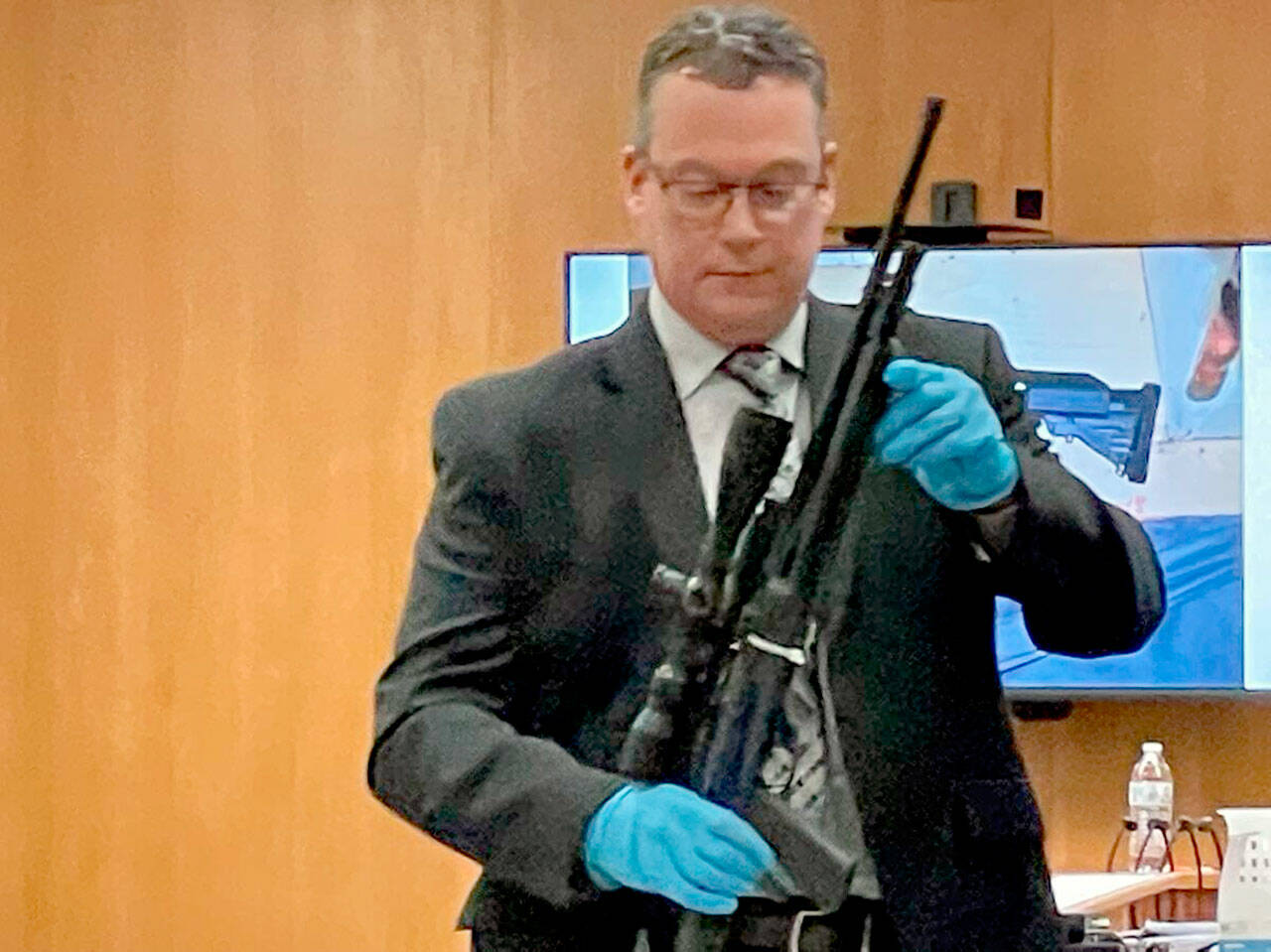 Detective Sgt. Eric Munger of the Clallam County Sheriffs Office prepares to show a semi-automatic rifle presented in the triple-murder trial of Dennis Marvin Bauer. (Paul Gottlieb/Peninsula Daily News)