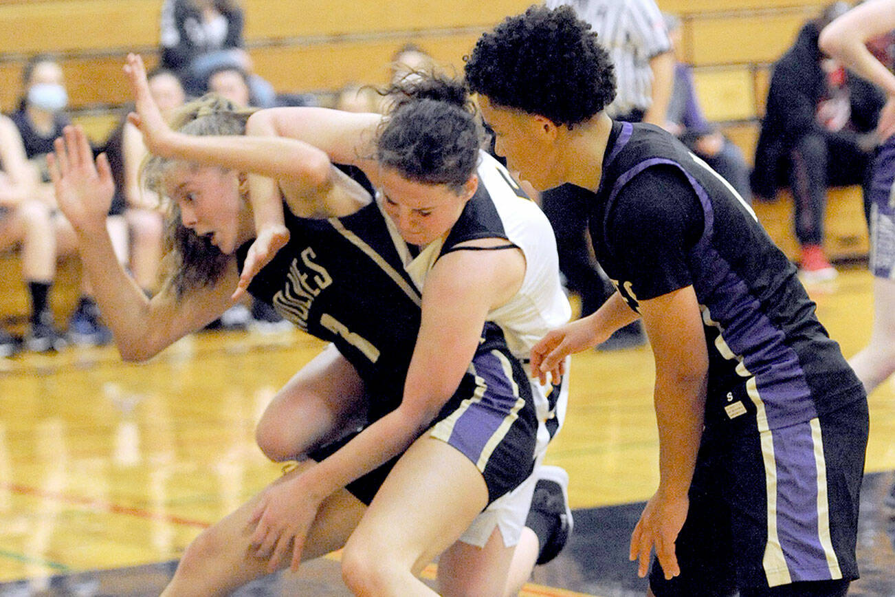 Lonnie Archibald/for Peninsula Daily News
Sequim's Sammie Bacon, left, and Forks' Keiri Johnson battle in the key while Sequim's Bobbie Mixon, right, looks on. The Sequim girls won 61-44.