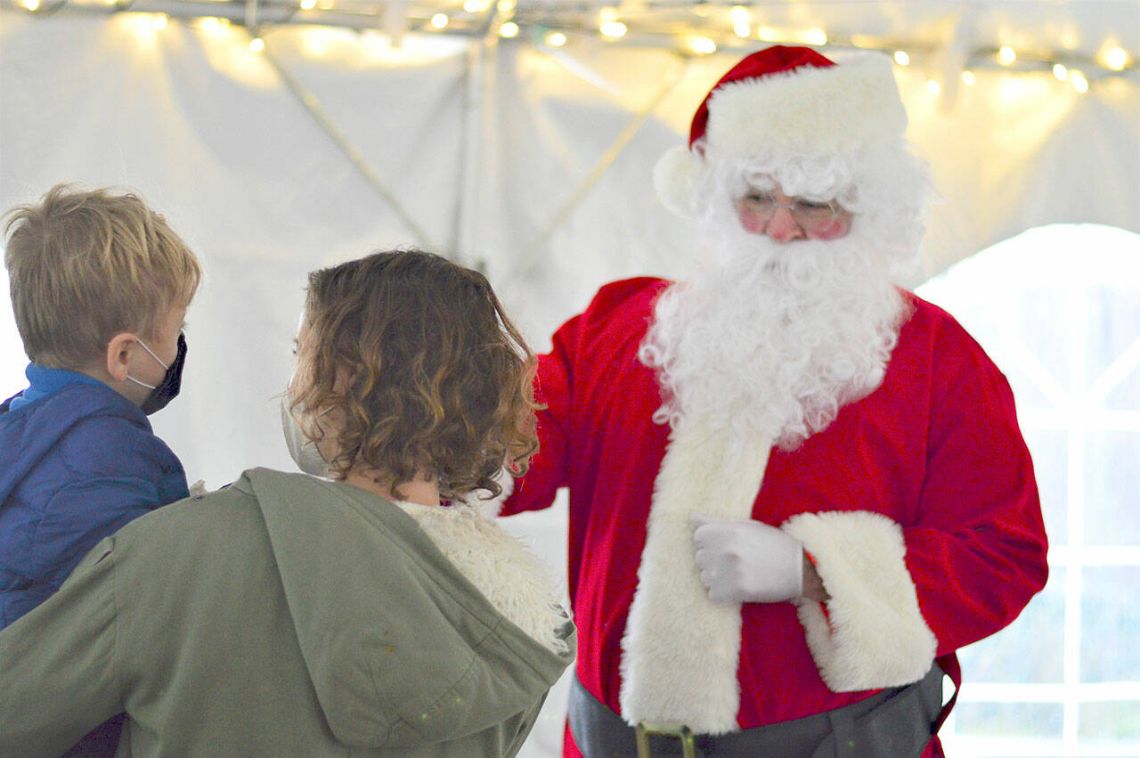 Dashiell Lemay, 4, supported by mom Amy Lemay of Port Townsend, fist-bumped with Santa Claus under the Tyler Street Plaza tent in Port Townsend on Saturday afternoon during the Port Townsend Main Street's seasonal activities that included a tree-lighting at dusk.   Diane Urbani de la Paz/Peninsula Daily News
