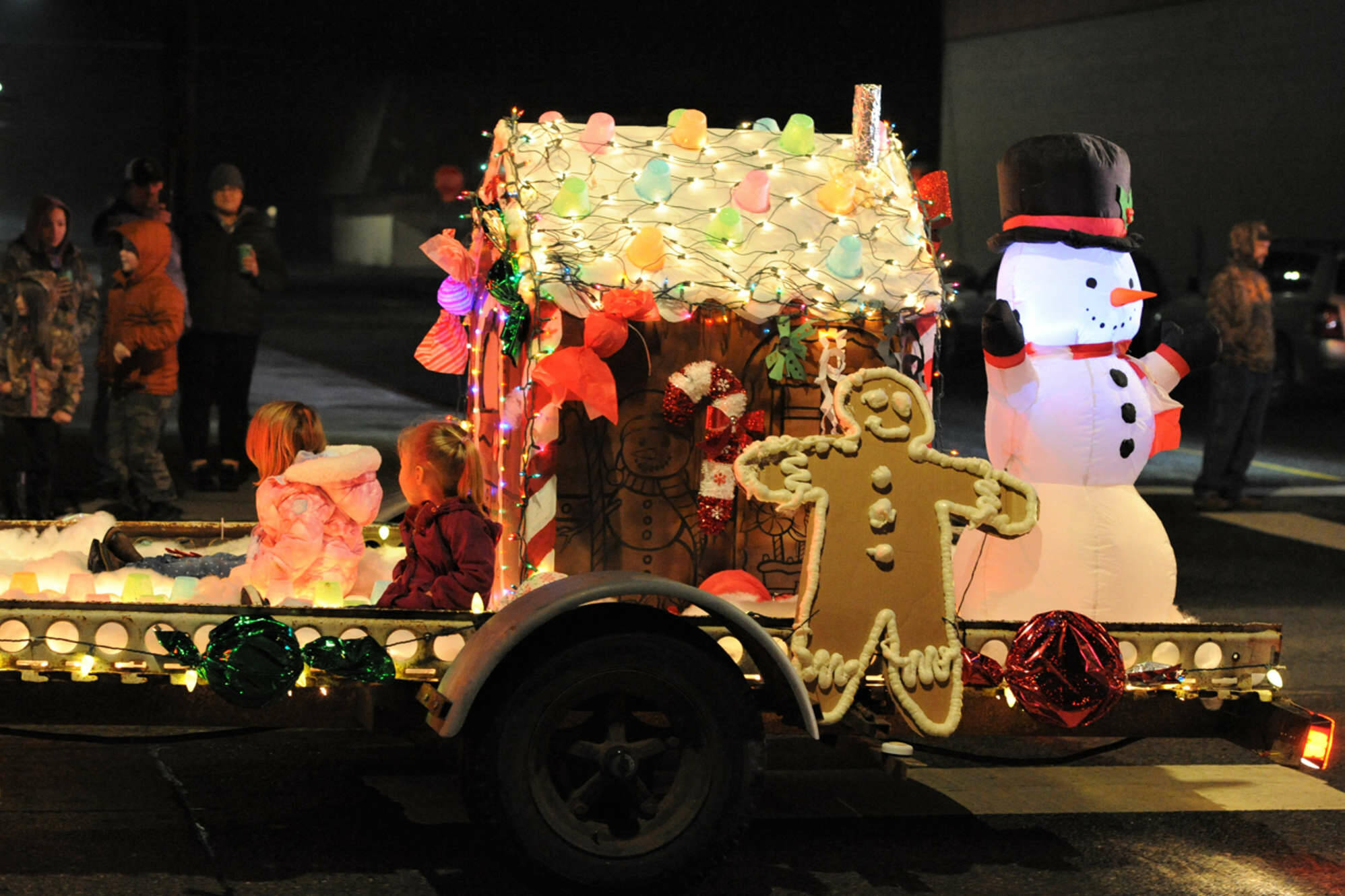 Kenzie Bechtold and Emery Fletcher ride in a gingerbread float created by Melissa Hitzfeld, Sarah Fletcher and Erica Bechtold during the Forks Twinkle Lights Parade on Saturday on Forks Avenue. (Lonnie Archibald/for Peninsula Daily News)