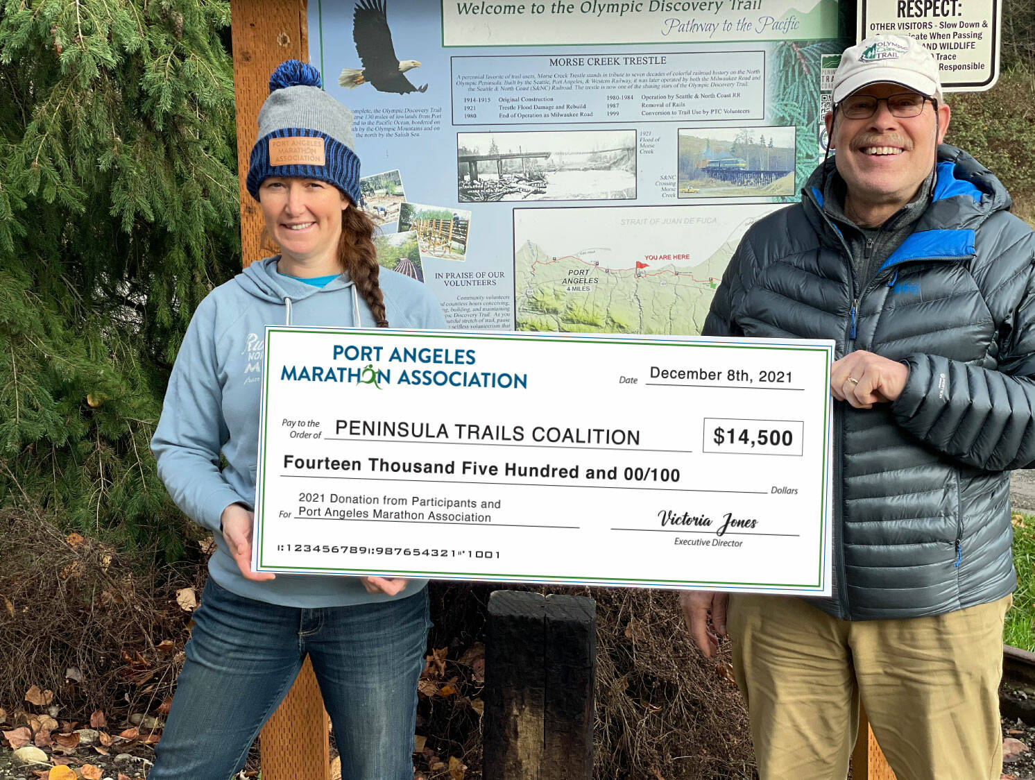 Jeff Bohman, Peninsula Trails Coalition, receives a donation check from Race Director Victoria Jones at the Morse Creek Olympic Discovery Trail trailhead. (Photo courtesy Dave Lasorsa)