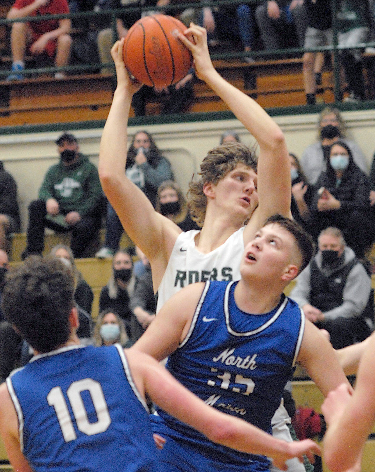 Keith Thorpe/Peninsula Daily News Port Angeles’ John Vaara, top, goes up and over the defense of North Mason’s Boston Stanley and Nick Minaker, left, on Thursday night at Port Angeles High School.