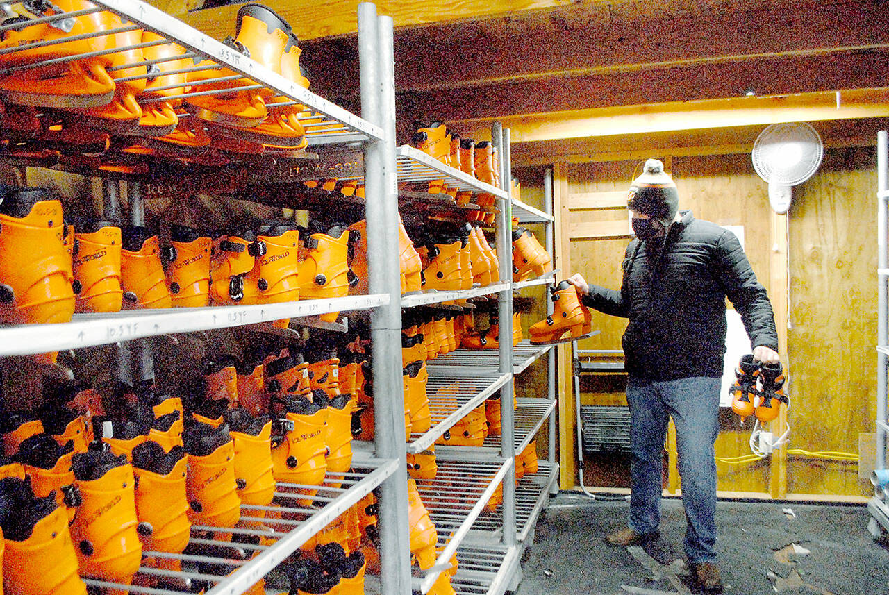 Volunteer Chris McCalla of Port Angeles, a senior chief at U.S. Coast Guard Air Station/Sector Field Office Port Angeles, pulls ice skates from a rack at the Port Angeles Winter Ice Village. (Keith Thorpe/Peninsula Daily News)