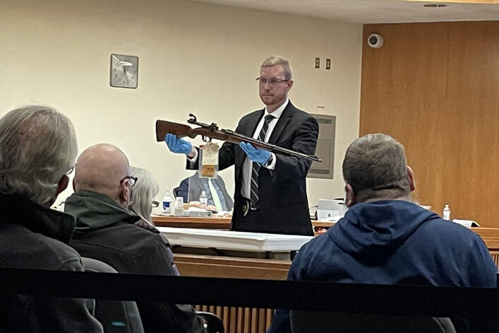 Rob Ollikainen / for Peninsula Daily News
Port Townsend Police Detective Jon Stuart holds a rifle that he found at Dennis Marvin Bauer’s residence in January 2019. Stuart was one of four witnesses to testify in Bauer’s triple-murder trial Monday morning in Clallam County Superior Court.