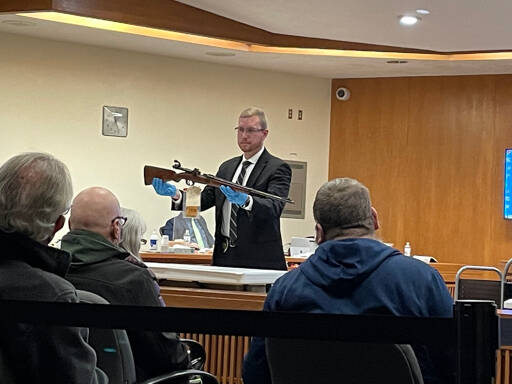 Rob Ollikainen / for Peninsula Daily News
Port Townsend Police Detective Jon Stuart holds a rifle that he found at Dennis Marvin Bauer’s residence in January 2019. Stuart was one of four witnesses to testify in Bauer’s triple-murder trial Monday morning in Clallam County Superior Court.