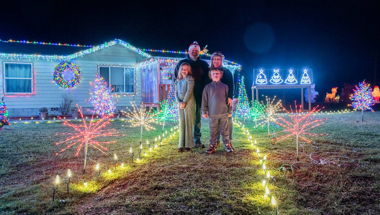 Emily Matthiessen / Olympic Peninsula News Group
The Bixby family, Emma, Corey, Tennille and Colin, stand in their yard, which they decorated with Christmas lights that are programmed to change with music.