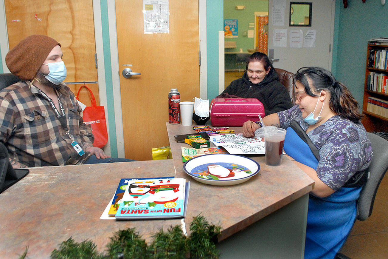 Keith Thorpe/Peninsula Daily News
Serenity House shelter aid Mike Wiley, left, sits at the front desk with clients Debra Roberts and Renee Mata, right, on Saturday at the Port Angeles homeless shelter prepares for a week of cold weather.
