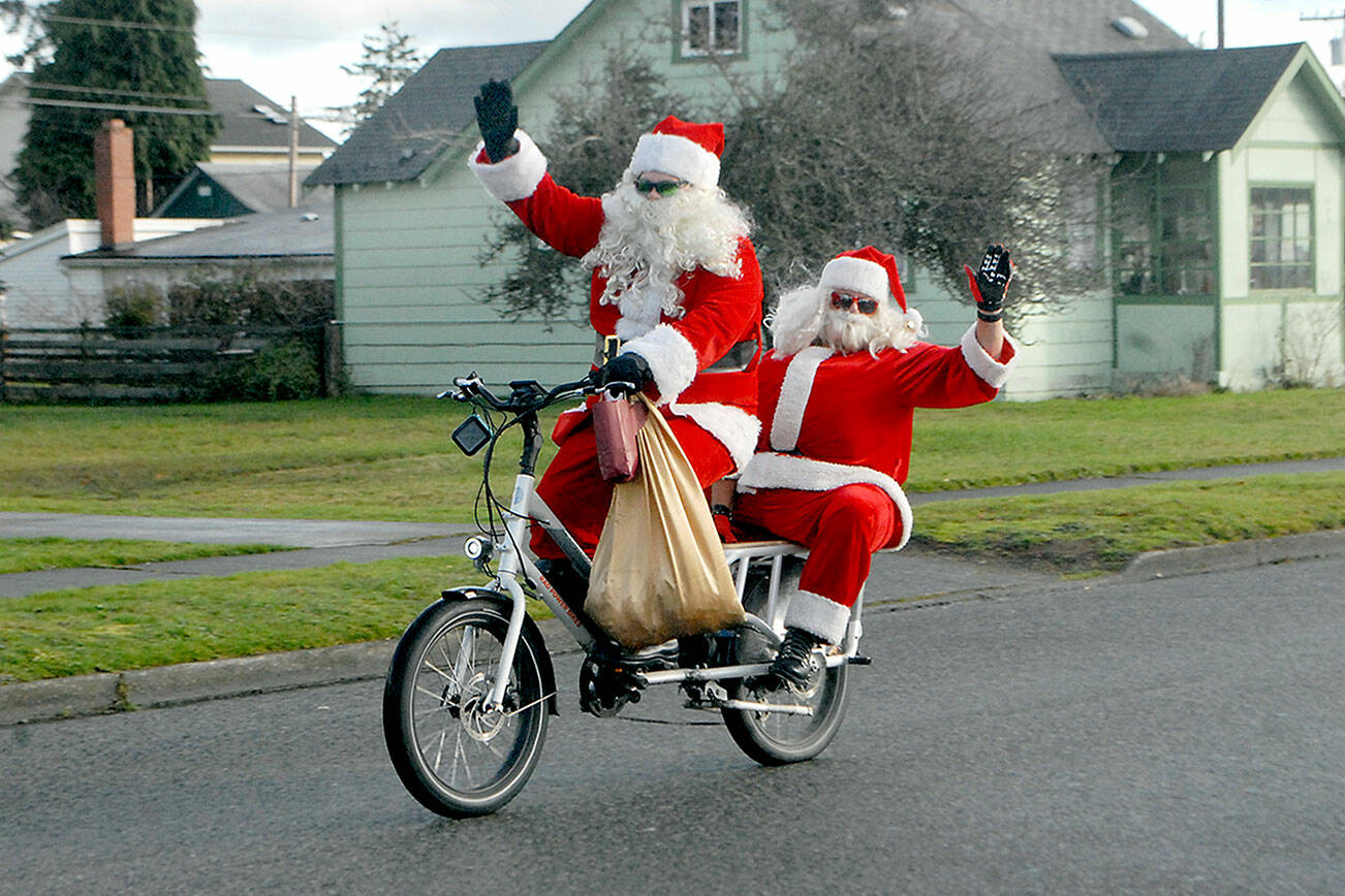 Keith Thorpe/Peninsula Daily News
Jake Thornburg, front, and Chig Martin, both of Port Angeles, take on the Santa persona as they ride a motorized bicycle on West Third Street in Port Angeles on Christmas Eve Day. The pair said the were out to bring good cheer to people for the holidays.