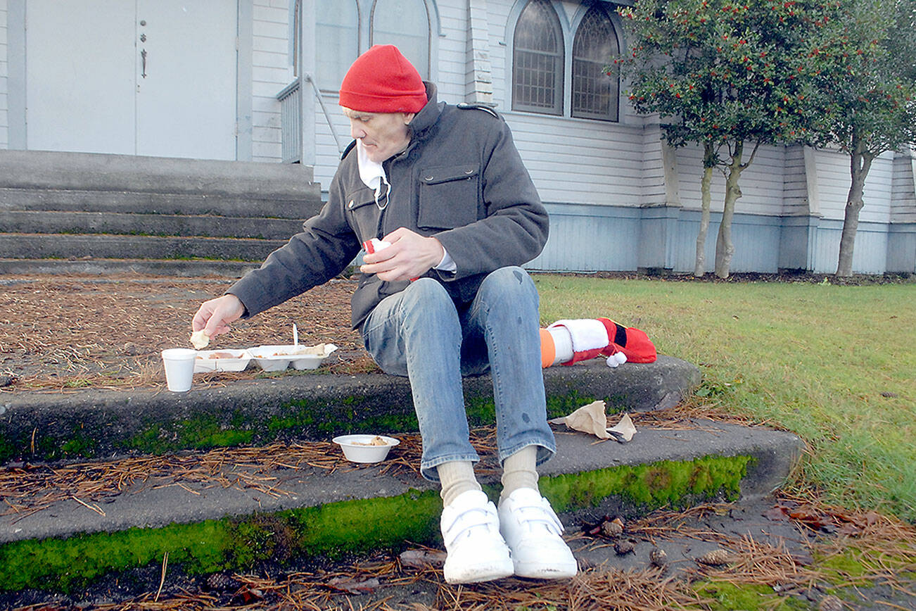 Keith Thorpe/Peninsula Daily News
Michael Freestone of Port Angeles sits on the steps in front of the Salvation Army Church in Port Anageles as he enjoys a carry-out Christmas Eve lunch. The organization served dozens of lunches with an outdoor dining twist in its annual holiday tradition.
