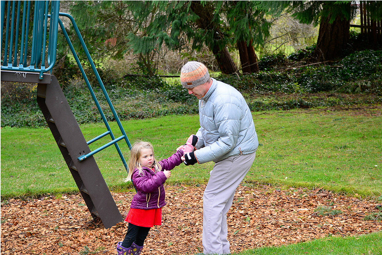 Mark Senffner of Portland, Ore., helps daughter Fionn, 3 ½, with her mittens during a Christmas Eve visit to Chetzemoka Park in Port Townsend. The pleasant but chilly weather on Friday turned colder on Saturday with overnight snow forecast. Diane Urbani de la Paz/Peninsula Daily News