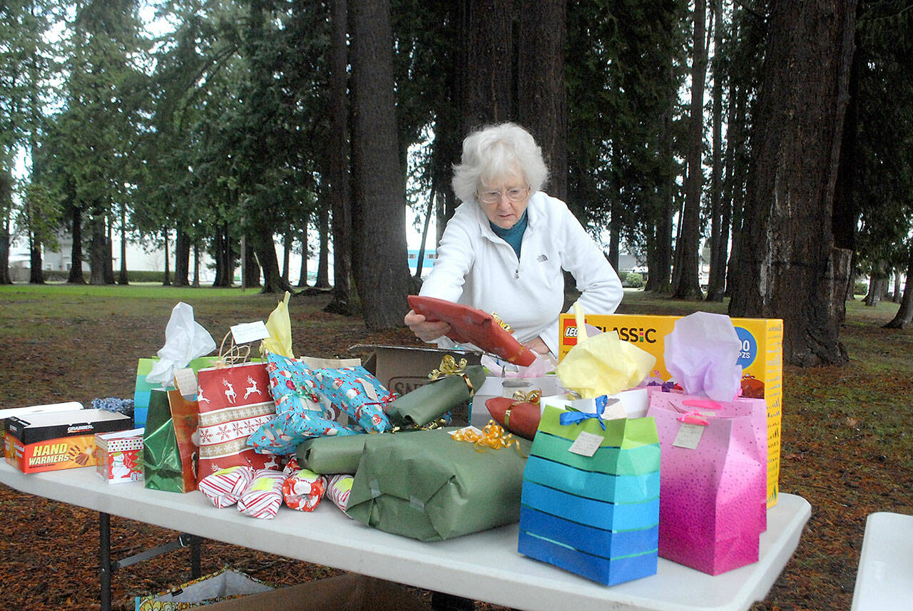 Ingrid Carmean of Port Angeles, a member of Food Not Bombs, an international group dedicated to assisting and feeding homeless individuals, sets up a table filled with Christmas presents on Saturday at Jesse Webster Park in Port Angeles.  The presents, along with a hot lunch, were distributed to needy individuals on Christmas Day, one of the group's every-other-weekend community meals. (Keith Thorpe/Peninsula Daily News)