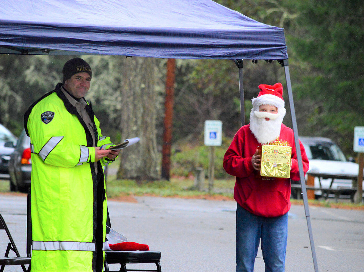 Jefferson County Sheriff’s Department Undersheriff Andy Pernsteiner, left, and Daltry Lammers, 12, of Chimacum greeted droves of people outside the Tri-Area Community Center in Chimacum on Saturday afternoon, where volunteers dished up 498 Christmas meals to go. Many people made reservations, organizer Rita Hubbard said, but quite a few called on Christmas Day asking if they could have a takeout dinner. “Come right now and we’ll get you fed,” Hubbard told the last-minute callers. (Diane Urbani de la Paz/Peninsula Daily News )