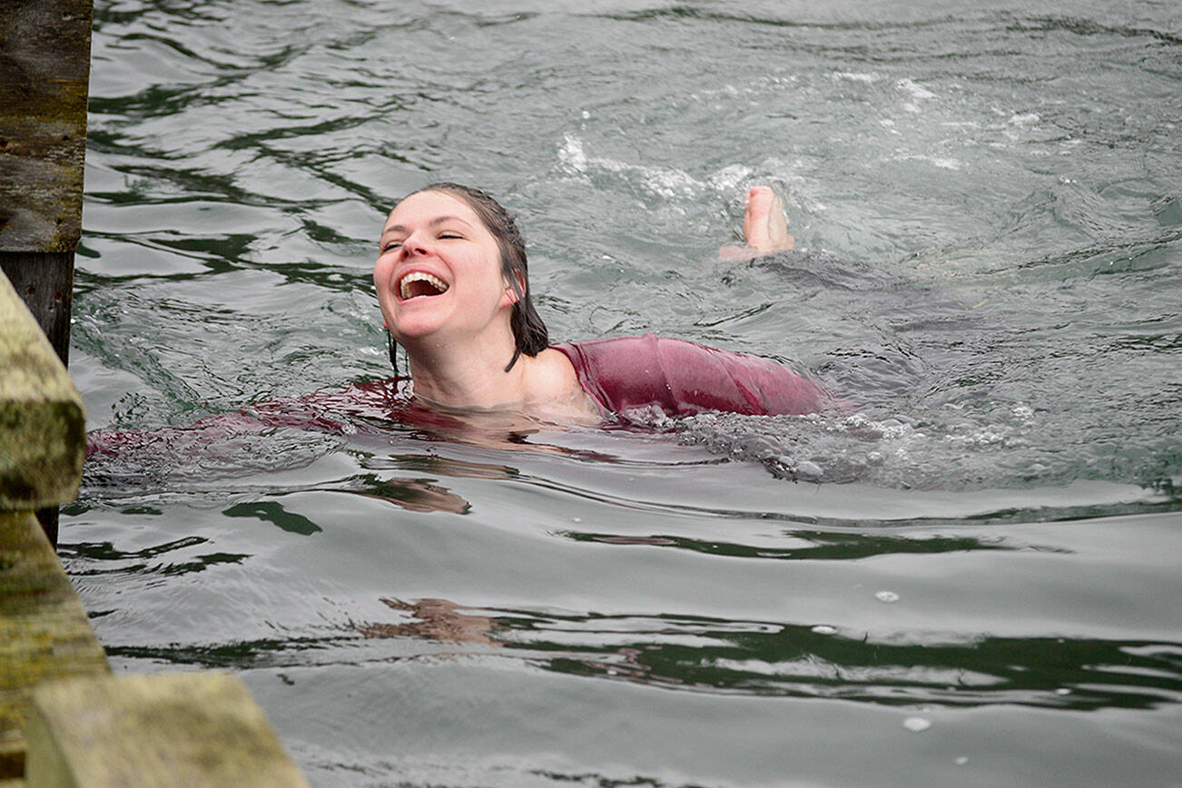 Graceful as a sea lioness, Laura Rogers of Port Hadlock takes the plunge off the dock on New Year’s Day 2021. (Diane Urbani de la Paz/Peninsula Daily News)