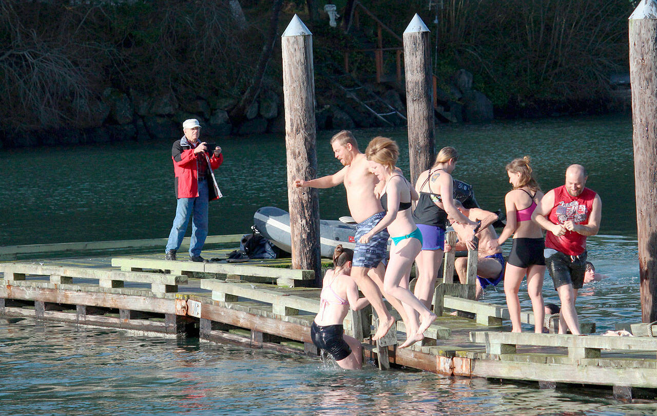 Two participants in the Nordland Polar Plunge jump off the dock in front of the Nordland General Store to celebrate the new year in 2020. (Zach Jablonski/Peninsula Daily News)