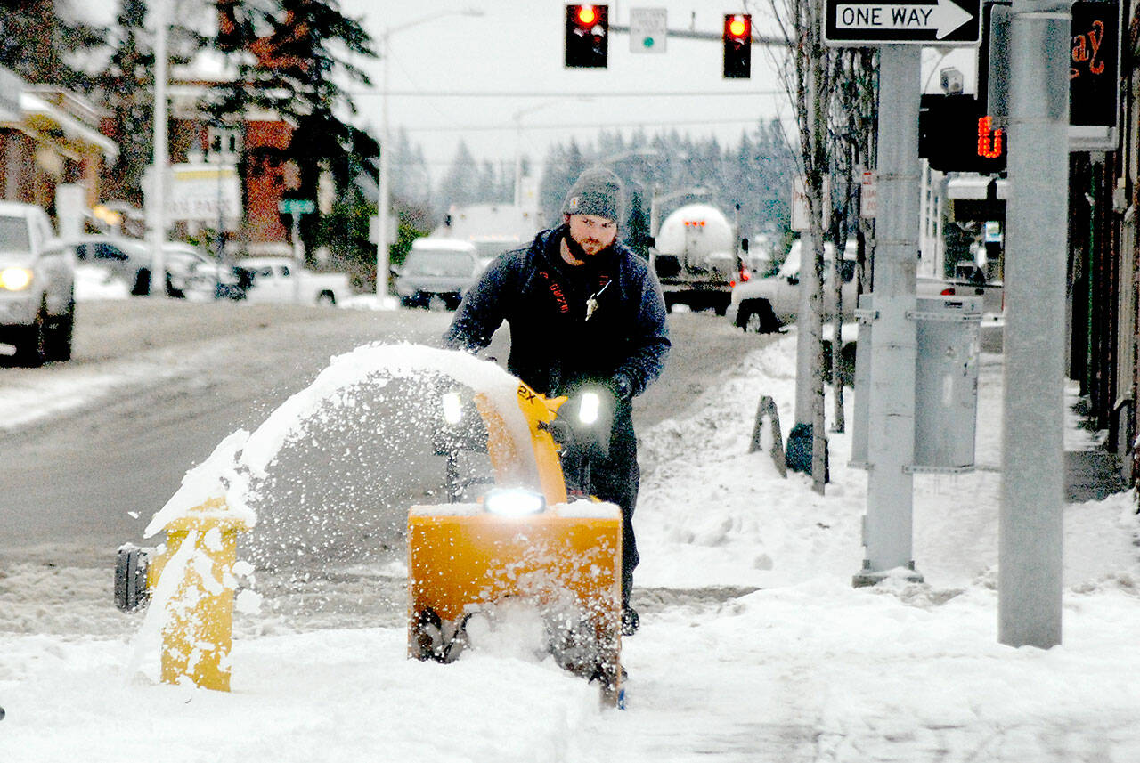 Port Angeles Parks and Recreation Department employee Lukas Cox uses a snowblower to clear a sidewalk at The Gateway at Front and Lincoln streets on Thursday. (Keith Thorpe/Peninsula Daily News)