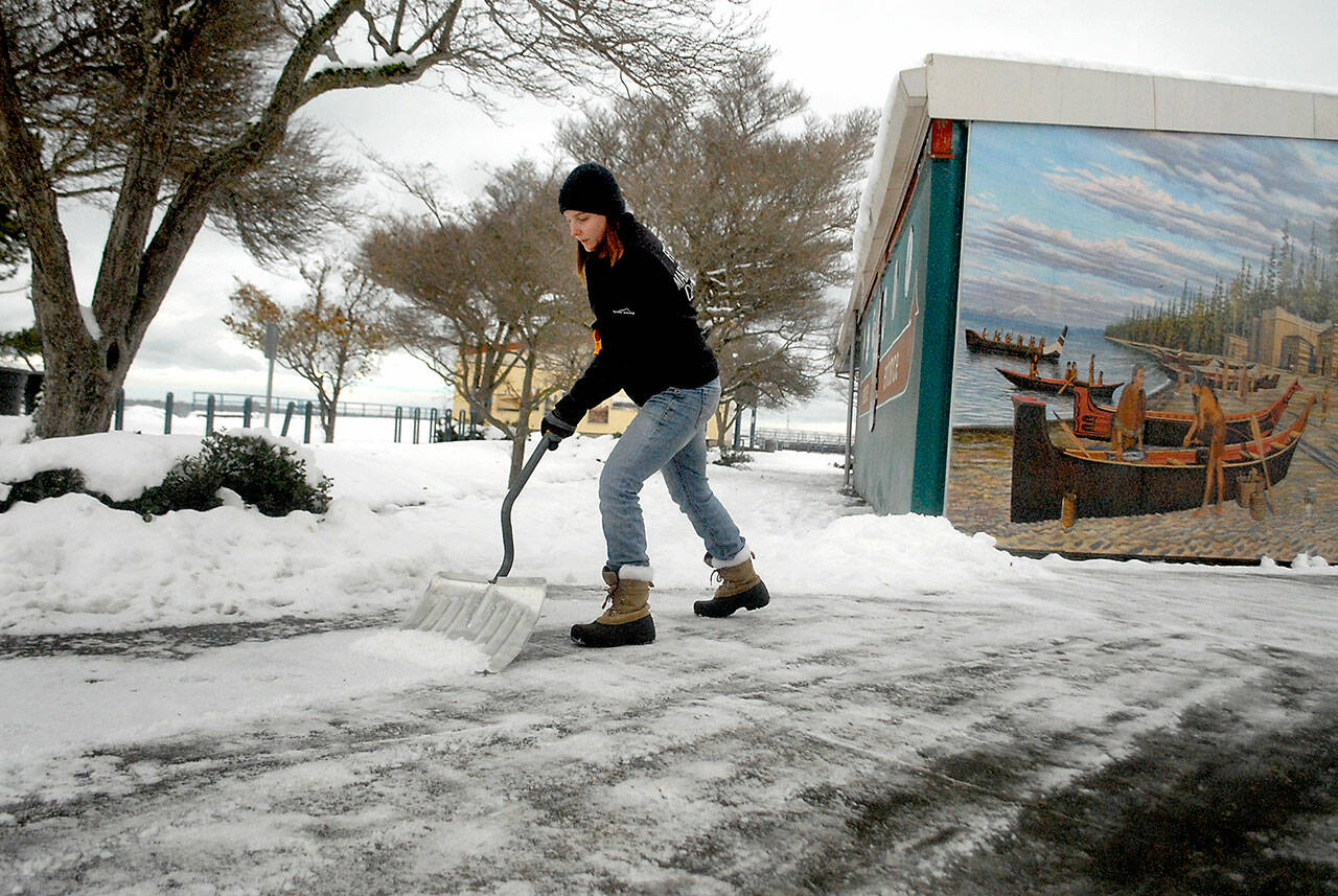 Feiro Marine Life Center Education Manager Rachele Brown clears a layer of newly fallen snow from the front of the building on Thursday at Port Angeles City Pier. (Keith Thorpe/Peninsula Daily News)