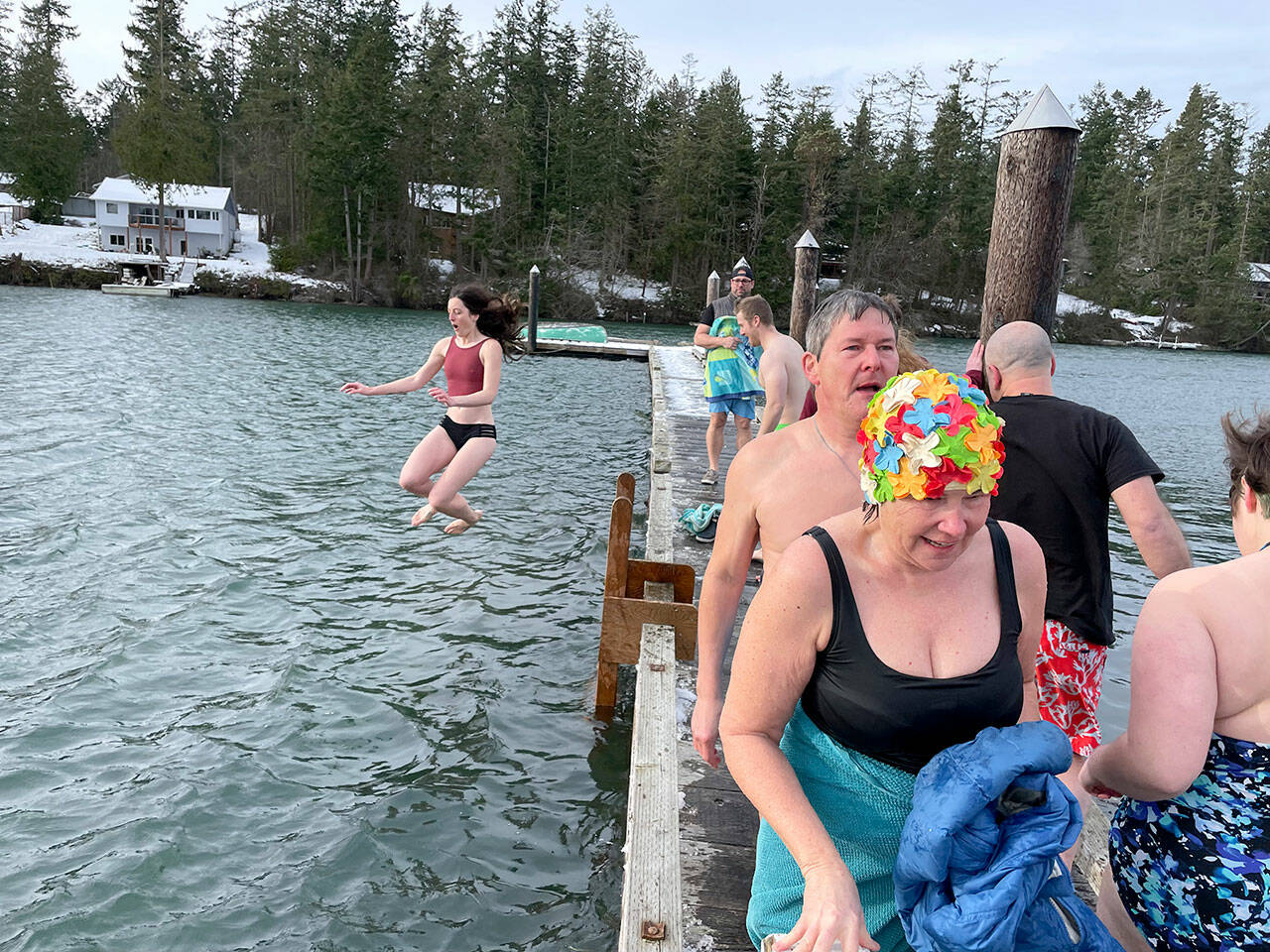 Theresa Britschg of Seattle and Chuck Sparks of Marrowstone Island walk back to the Nordland General Store after jumping into the chilly waters of Mystery Bay off the dock outside the store on Saturday. Behind them, Anna Watt of Marrowstone Island is captured in mid-jump. (photo by Will ODonnell)