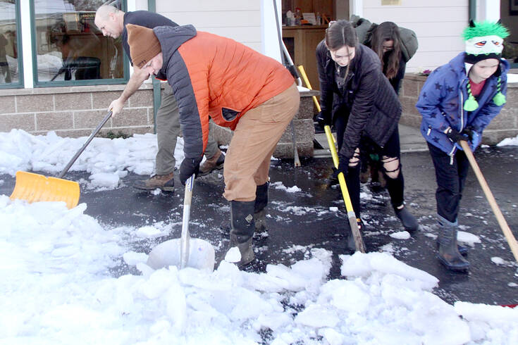 From left to right, John Glass, Scott VanDyken, Rileigh VanDyken, 17, and Isaak VanDyken, 10, scrape and shovel snow and ice away from the VanDyken Family Dentistry building in the 600 block of east Eighth Street in Port Angeles. A total of nine people volunteered to clear the sidewalks as the holiday break came to an end. (Dave Logan/for Peninsula Daily News)
