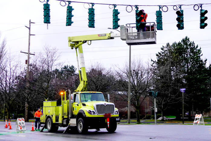 A state Department of Transportation crew fixes a wind-damaged stoplight on Monday at the intersection of state Highway 20 and Kearney Street in Port Townsend. Temperatures are expected to be in the upper 30s and low 40s this week with rain in the forecast. (Steve Mullensky/for Peninsula Daily News)