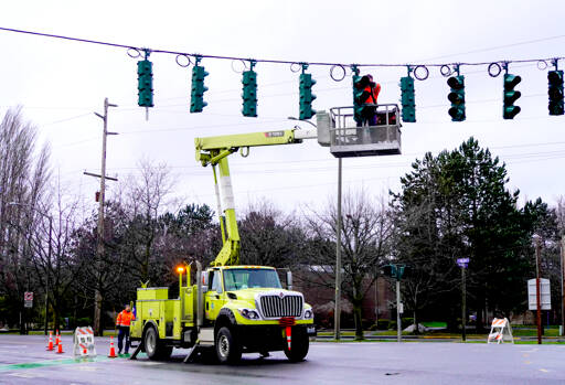 A state Department of Transportation crew fixes a wind-damaged stoplight on Monday at the intersection of state Highway 20 and Kearney Street in Port Townsend. Temperatures are expected to be in the upper 30s and low 40s this week with rain in the forecast. (Steve Mullensky/for Peninsula Daily News)