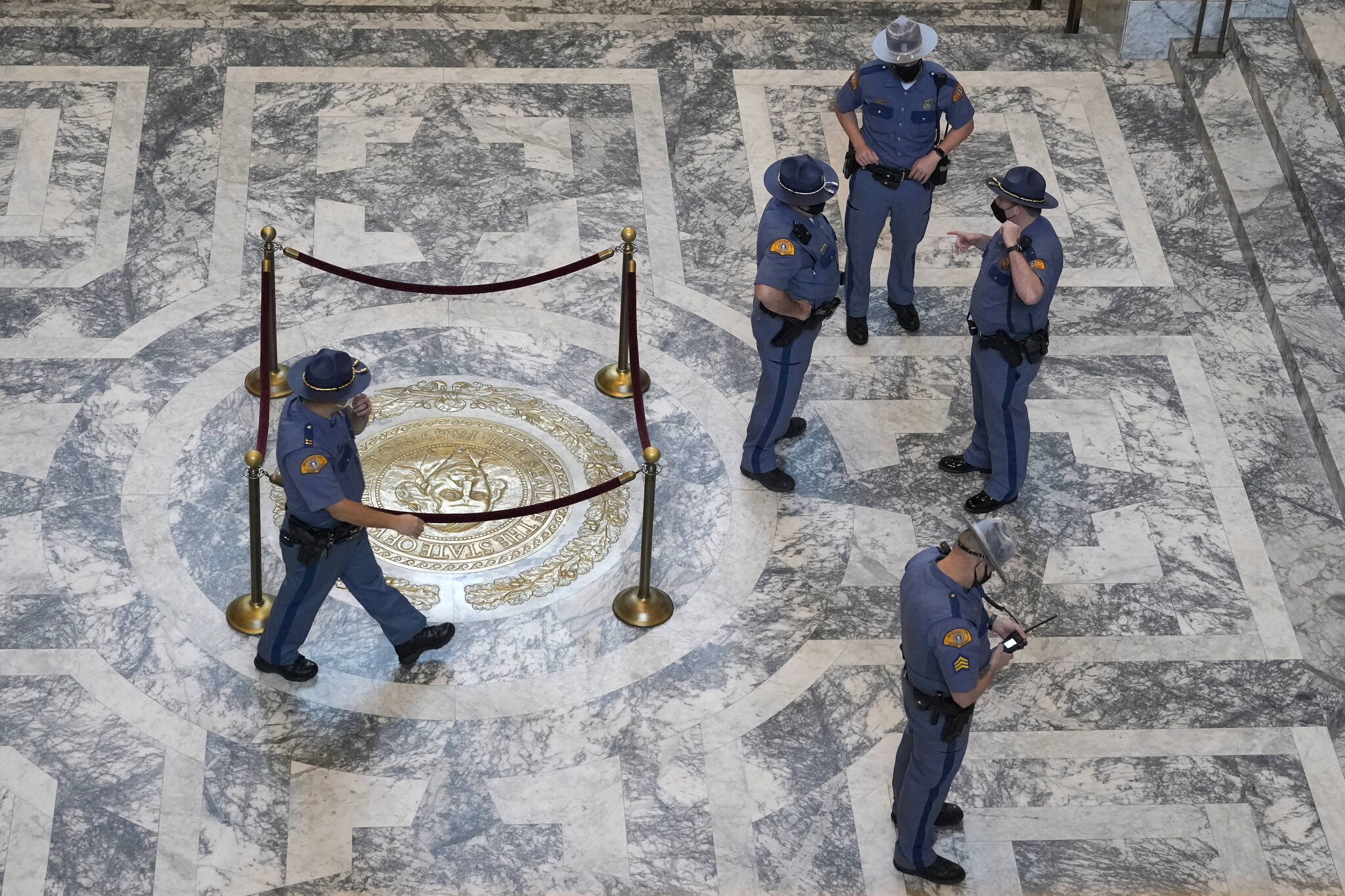 Washington State Patrol troopers stand near the state seal in the rotunda of the Legislative Building, Tuesday, Jan. 11, 2022, before Gov. Jay Inslee's scheduled State of the State address at the Capitol in Olympia, Wash. Due to cautions against COVID-19, Inslee will give the speech in the State Reception Room and it will be shown by streaming video to lawmakers meeting remotely. (AP Photo/Ted S. Warren)