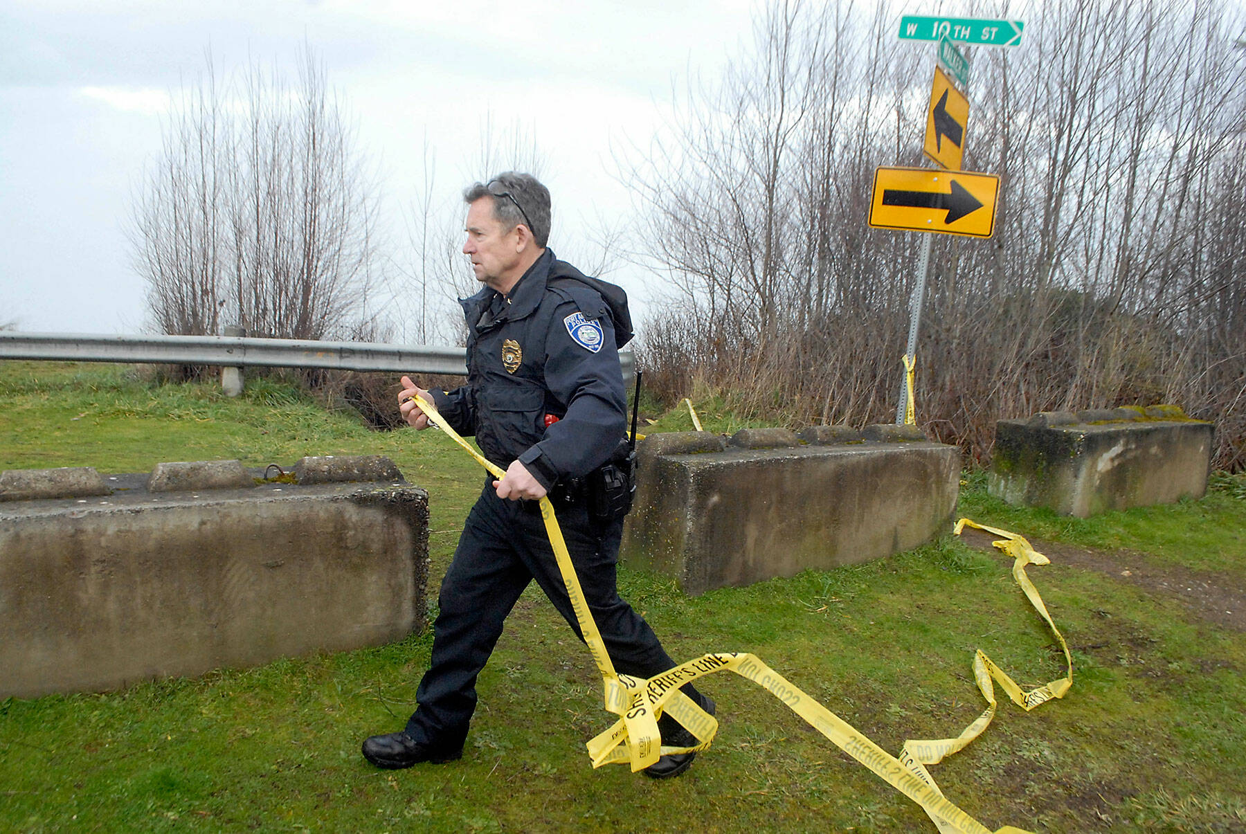 Port Angeles Police Chief Brian Smith stretches caution tape around an area of unstable bluff at 10th and Walker streets in Port Angeles on Wednesday. (Keith Thorpe/Peninsula Daily News)
