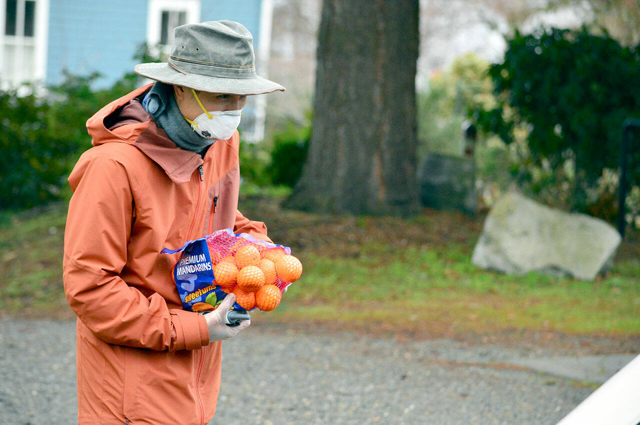 Volunteer Meso Tadeo accepted a donation of a bag of oranges from a passerby outside St. Paul’s Episcopal Church last week. (Diane Urbani de la Paz/Peninsula Daily News)