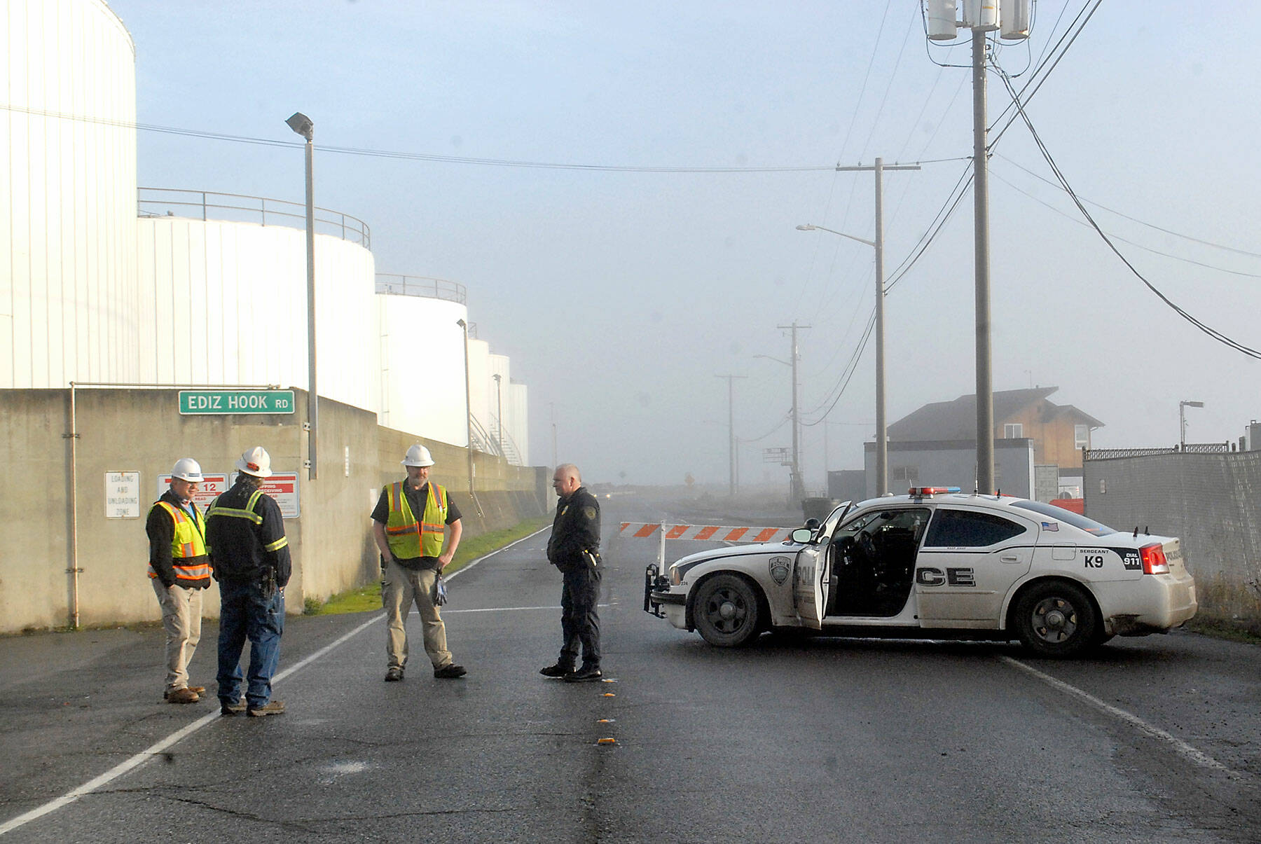 Port Angeles police Sgt. Kevin Miller, right, speaks with officials ot the McKinley Paper Co., as his police cruiser blocks Ediz Hook Road after as the hook was being evacuated during a tsunami advisory on Saturday morning. (Keith Thorpe/Peninsula Daily News)