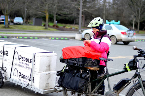 Juri Jennings, aka the Peddler, has been delivering Food Bank Farm & Gardens produce by electric bicycle to the Port Townsend Food Bank since the middle of last year. This year, she’s expanding to include deliveries to people who cannot get to the food pantry. (Diane Urbani de la Paz/Peninsula Daily News)