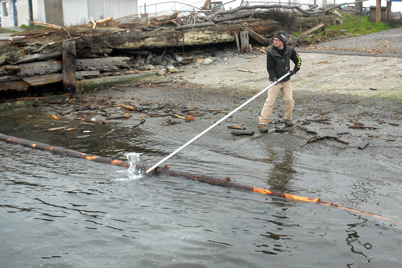 Port Angeles Parks and Recreation Department employee Eli Hammel snags a floating log blocking a portion of a city-operated boat ramp on Ediz Hook on Thursday. The log was later removed with a front loader and deposited with other woody debris nearby. (Keith Thorpe/Peninsula Daily News)