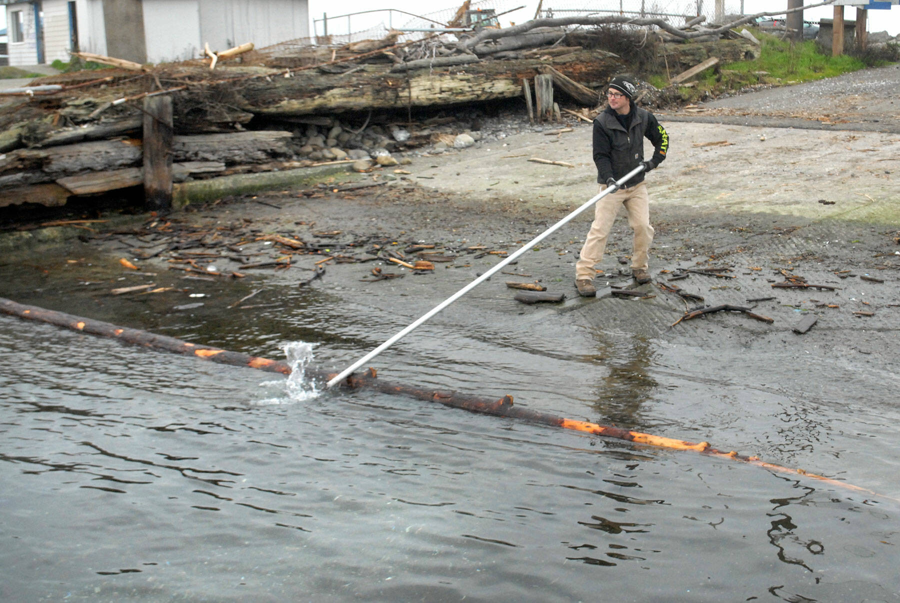 Port Angeles Parks and Recreation Department employee Eli Hammel snags a floating log blocking a portion of a city-operated boat ramp on Ediz Hook on Thursday. The log was later removed with a front loader and deposited with other woody debris nearby. (Keith Thorpe/Peninsula Daily News)