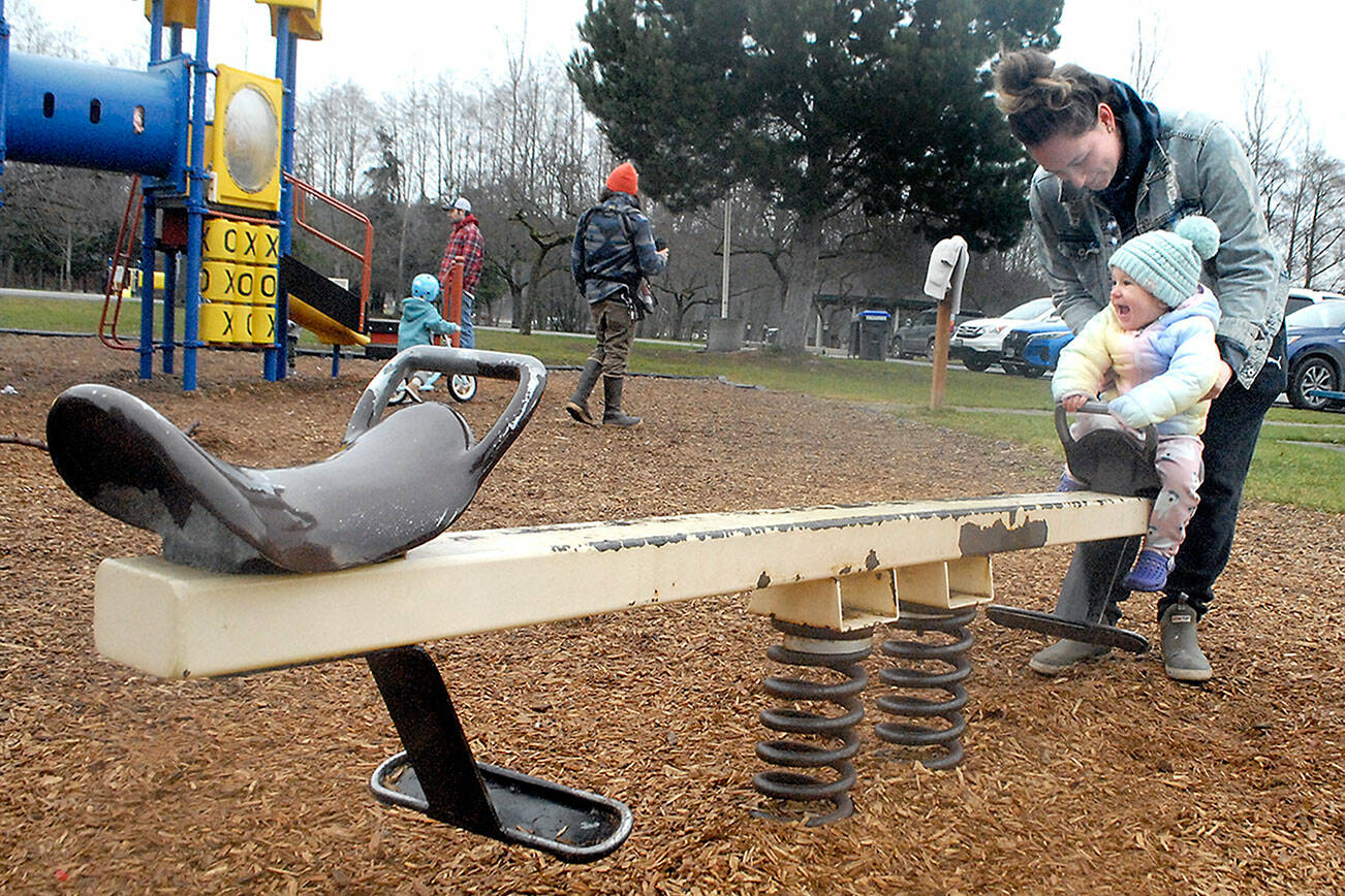 Keith Thorpe/Peninsula Daily News
Rowan McCreary, 1, takes delight on riding a spring-loaded teeter totter as her mother, Autumn Wolfgang of Sequim, adds the bounce on Saturday at Carrie Blake Park in Sequim.
The pair was on a family outing to the playground and dog park.