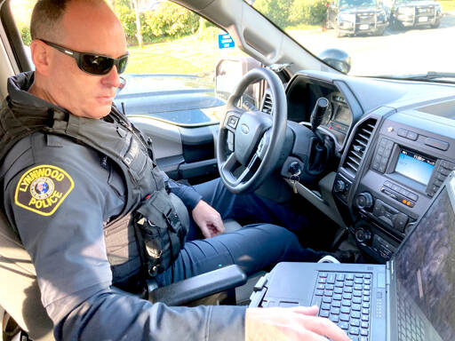 Lynnwood police Officer Denis Molloy works in his vehicle in November. Molloy, of the Lynnwood Police Department’s community health and safety section, says navigating recent police reforms in Washington State has been challenging. (Gene Johnson/The Associated Press)