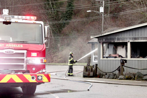 Ethan Grossell of the Port Angeles Fire Department cools hot spots left over from a fire at Castaways Restaurant Lounge early Monday morning. (Dave Logan/for Peninsula Daily News)