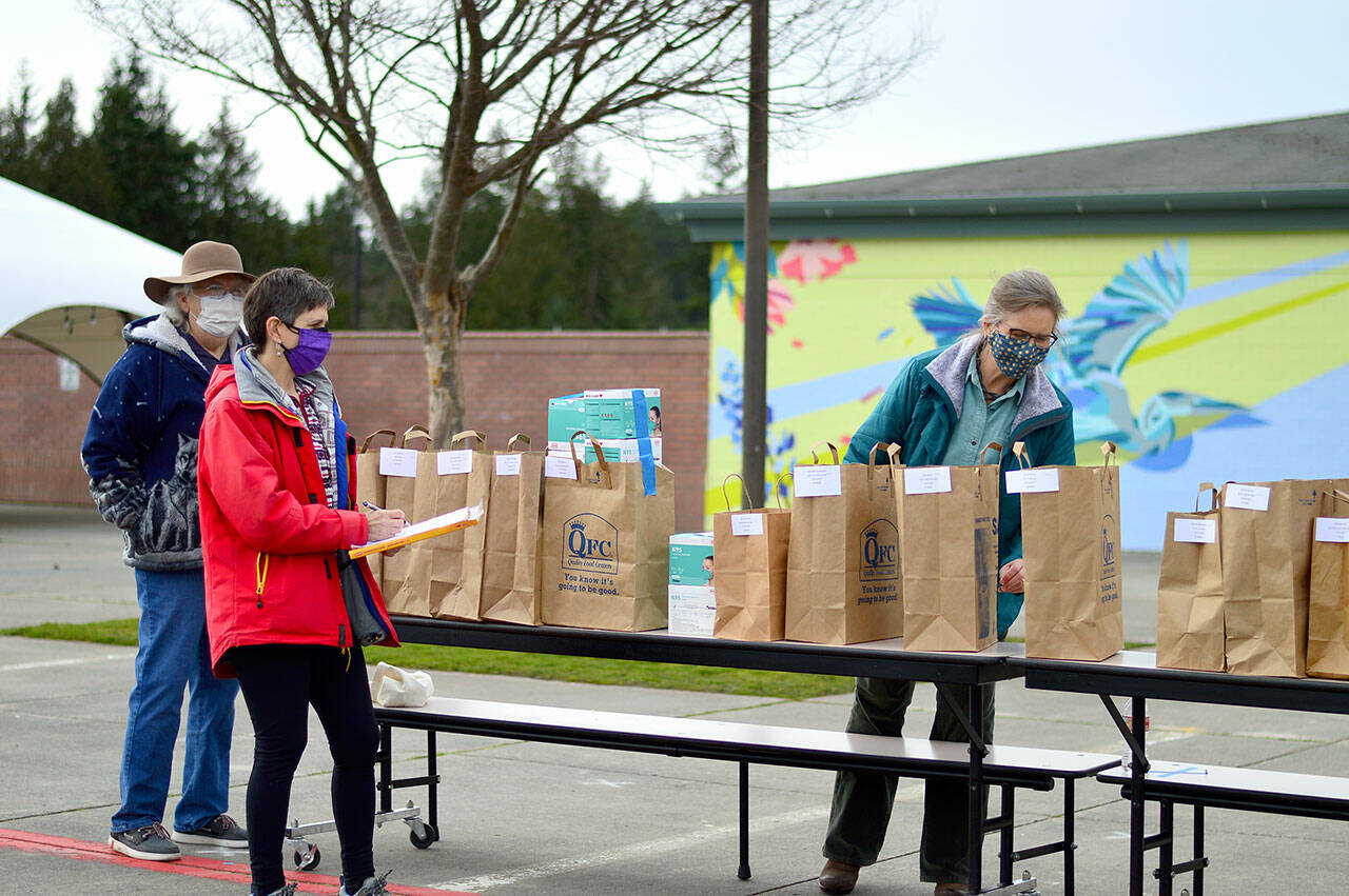 Local 20/20 volunteers — from left, Margaret Backer of Port Hadlock, Elizabeth Bindschadler of Quilcene and Deborah Stinson of Port Townsend — hand out thousands of free N95 masks on Saturday at Port Townsend’s Blue Heron Middle School. The effort was organized by NPREP, Local 20/20’s countywide neighborhood preparedness action group. (Diane Urbani de la Paz/Peninsula Daily News)
