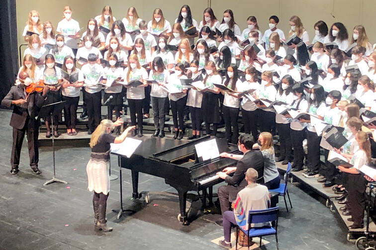 Jolene Dalton Gailey of Port Angeles conducts the Junior All-State Treble Choir in concert at the Capitol Theatre last Saturday with James Ray, Gailey’s former Port Angeles High School colleague, playing violin at left. (Monika Tabor)