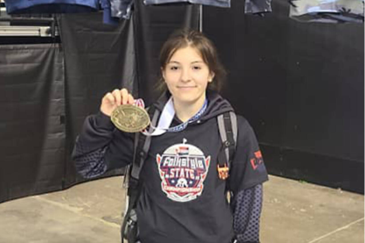 Port Angeles’ Natalie Johnson shows off her first-place medal she won at the state folkstyle wrestling tournament held Sunday at the Tacoma Dome.