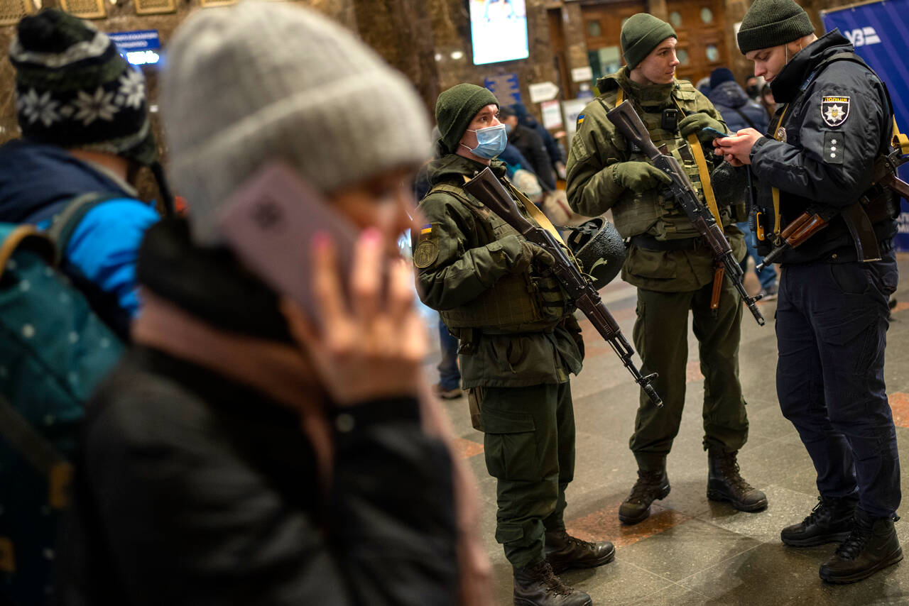 Ukrainian soldiers stand guard as people try to leave at the Kyiv train station, Ukraine, Thursday, Feb. 24, 2022. Russian troops have launched their anticipated attack on Ukraine. Big explosions were heard before dawn in Kyiv, Kharkiv and Odesa as world leaders decried the start of an Russian invasion that could cause massive casualties and topple Ukraine's democratically elected government. (AP Photo/Emilio Morenatti)